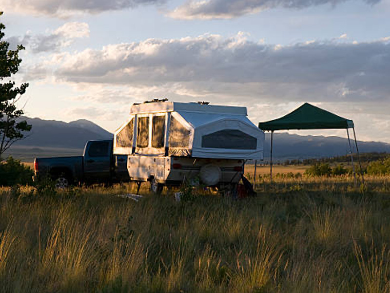 Camper parked in a field at sunset