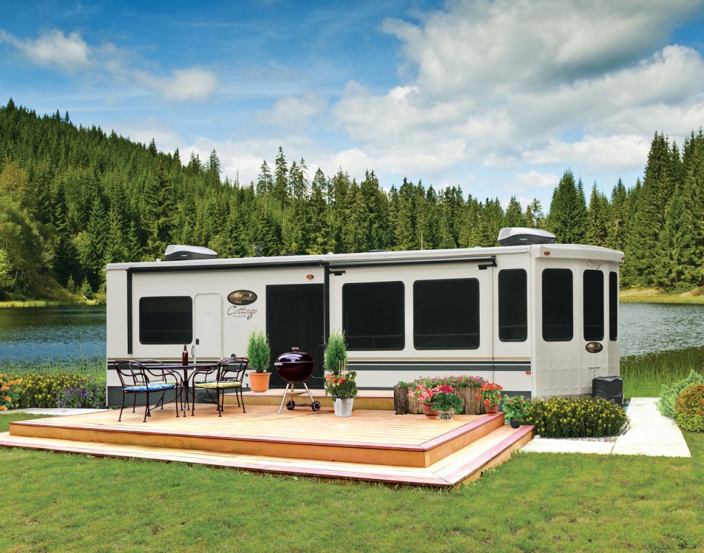 RV parked with a deck by a lake